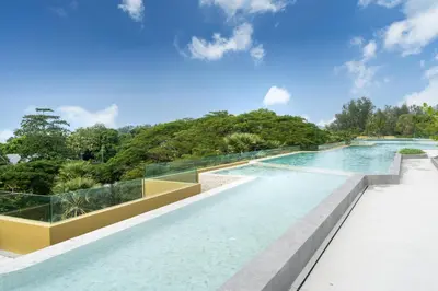 an infinity pool with glass walls and trees at Laguna Beachside 1 bedroom apartment 2 minutes from the beach in Phuket Town