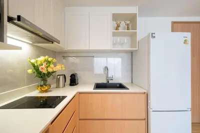 a kitchen with a white refrigerator and a vase of flowers at Laguna Beachside 1 bedroom apartment 2 minutes from the beach in Phuket Town