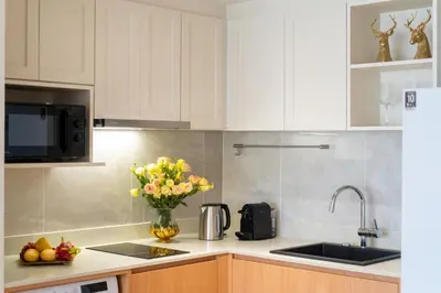 a kitchen with white cabinets and a vase of flowers at Laguna Beachside 1 bedroom apartment 2 minutes from the beach in Phuket Town