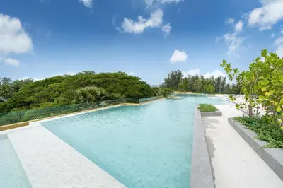 a swimming pool with blue water and trees in the background at Laguna Beachside 1 bedroom apartment 2 minutes from the beach in Phuket Town