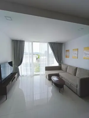 a living room with a couch and a television at Smart Conzept 2bdr 300m to the sea in Kata Beach