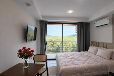 a hotel room with a bed and a vase of flowers on a table at MaiKhao Sunrise Sight Space in Ban Mai Salae