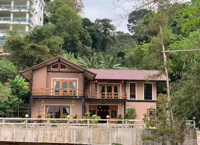 a house sitting on the side of a river at The Moonlight Guesthouse in Patong Beach
