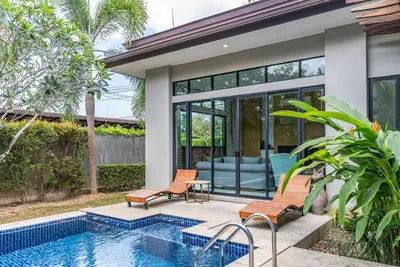 a home with a pool and two chairs next to a house at Tanode Villa 511 by Villacarte in Bang Tao Beach