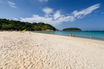 a beach with people and a yellow surfboard on it at Garden bungalows 4br with private pool in Rawai Beach