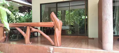 a wooden chair sitting on the porch of a house at Baan Suan Villas Resort in Ban Suan