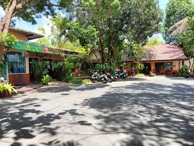a street in front of a building with trees at Baan Suan Villas Resort in Ban Suan