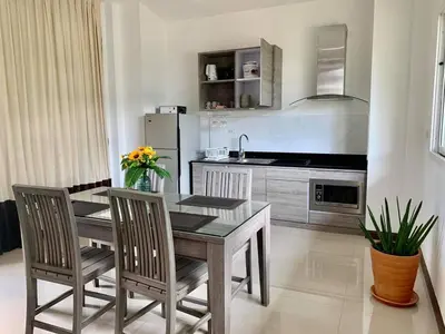 a kitchen with a wooden table and chairs in a kitchen at Private Pool Villa at Nai Harn 2 bedroom in Rawai Beach