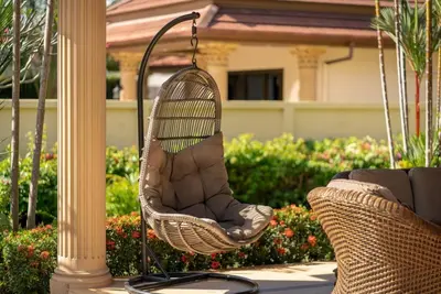 a wicker chair hanging from a pole on a porch at Villa Rodentia 3br pool Villa in Rawai Beach