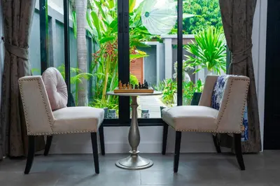 two chairs and a chess board on a table in front of a window at Villa Charming - Lovely 2 bedrooms house with pool in Rawai Beach