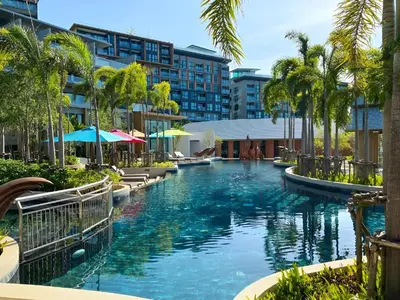 a pool at a resort with palm trees and buildings at Mida Grande Apartment with Rooftop Pool near Surin Beach in Surin Beach