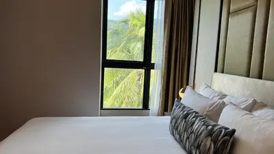 a bedroom with a large bed with a window at Mida Grande Apartment with Rooftop Pool near Surin Beach in Surin Beach