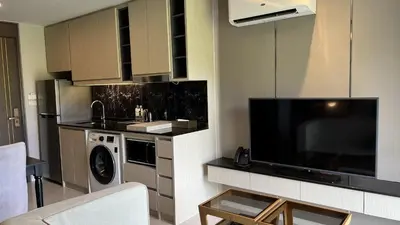 a kitchen with a large flat screen tv in a living room at Mida Grande Apartment with Rooftop Pool near Surin Beach in Surin Beach