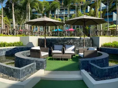 a patio with chairs and umbrellas next to a pool at Mida Grande Apartment with Rooftop Pool near Surin Beach in Surin Beach
