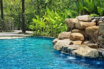 a pool with a waterfall and rocks in a yard at F1 The Title Residencies Naiyang Phuket 1 Floor 1 Bdr in Nai Yang Beach