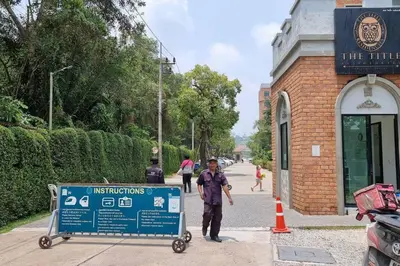 a man walking past a sign in front of a building at F1 The Title Residencies Naiyang Phuket 1 Floor 1 Bdr in Nai Yang Beach