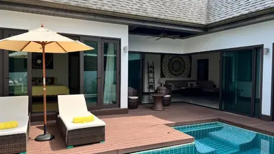a patio with a chair and an umbrella next to a pool at Plunge Tropic Pool Villa near Nai Harn Beach in Rawai Beach