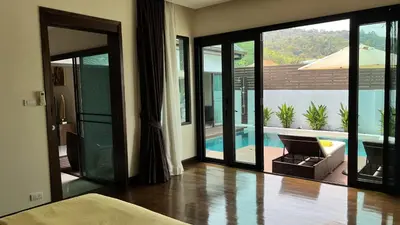 a bedroom with sliding glass doors leading to a pool at Plunge Tropic Pool Villa near Nai Harn Beach in Rawai Beach