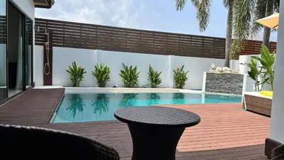 a swimming pool with a table and a chair on a deck at Plunge Tropic Pool Villa near Nai Harn Beach in Rawai Beach