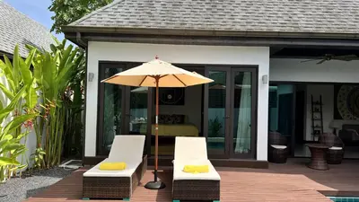 a patio with two chairs and an umbrella at Plunge Tropic Pool Villa near Nai Harn Beach in Rawai Beach