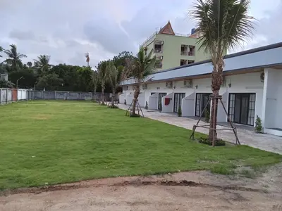 a large yard with palm trees in front of a building at Taxim Boutique Hotel in Patong Beach