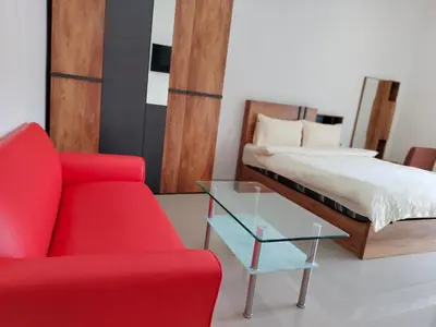 a bedroom with a bed and a red chair and a glass table at Taxim Boutique Hotel in Patong Beach