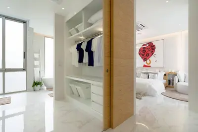a white bedroom with a bed and a bathroom at The Residence by Andaman Villa in Phuket Town
