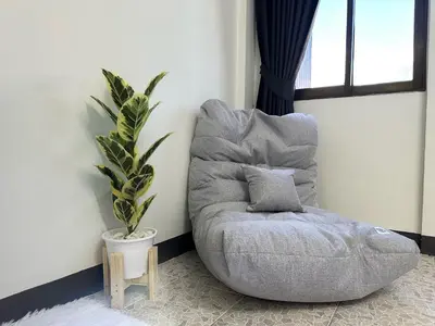 a gray chair in a room with a plant at MONTANA Hotel & Hostel Phuket in Karon Beach