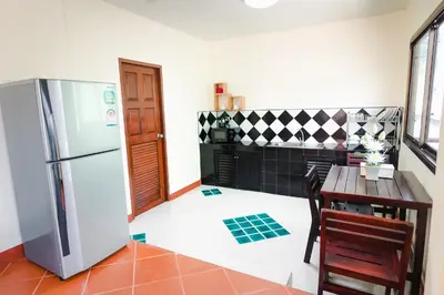 a kitchen with a refrigerator and a table with chairs at Kai Mook House in Ban Ket Ho